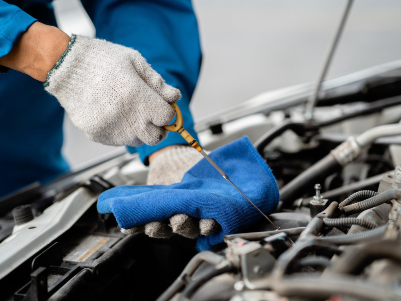Close-up, a car mechanic checking the oil in a car's engine