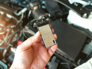 The mass air flow sensor of the engine air intake manifold system in auto mechanic hand, automotive part concept