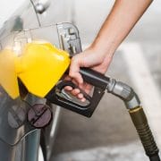 Close up hand of man pumping gasoline fuel in car at gas station