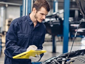 Mechanic holding a clipboard while checking the car condition