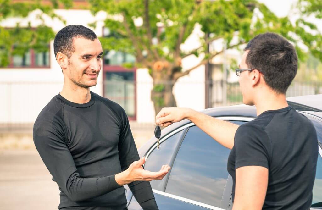 Happy satisfied young man receiving car keys after second hand sale - Concept business transport trade of modern luxury vehicles - Car rental assistance and insurance customer care