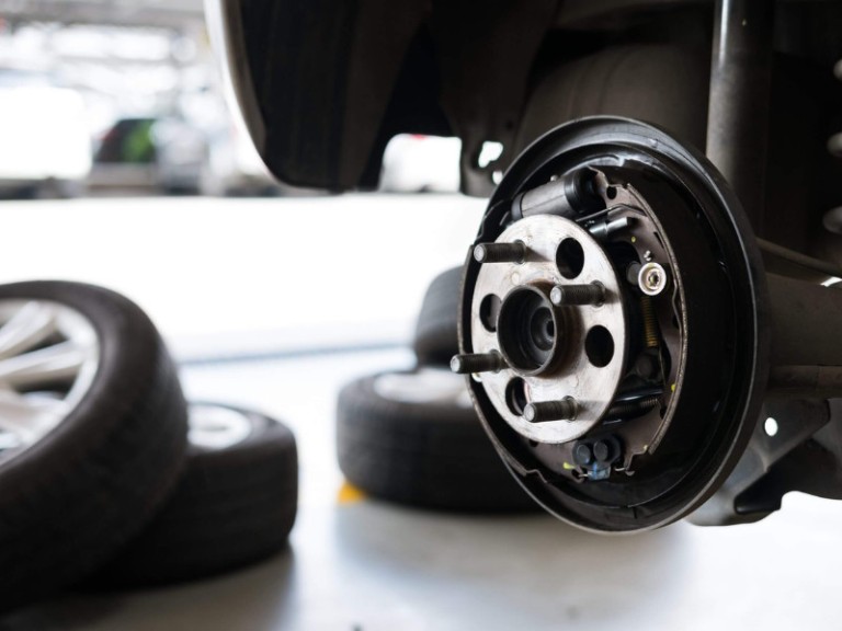 car suspension & bearing of wheel hub in auto service maintenance. Car lift up by hydraulic, waiting for tire replacement in garage. punched wheel concept