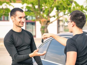 Happy satisfied young man receiving car keys after second hand sale - Concept business transport trade of modern luxury vehicles - Car rental assistance and insurance customer care