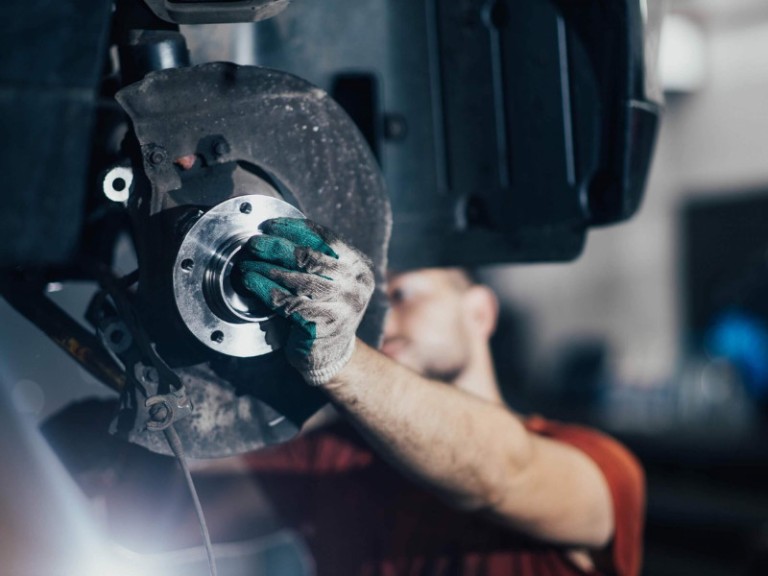 man changes a wheel hub with a wheel bearing in a car