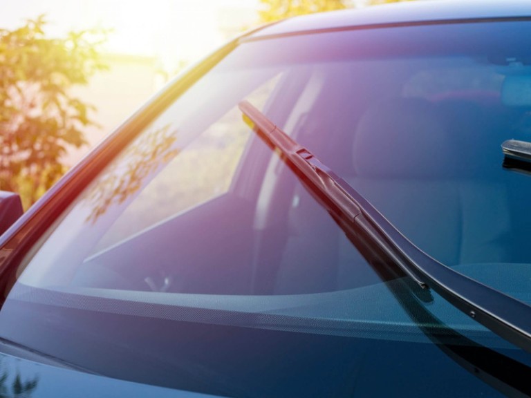 Brushes on the car glass with copy space. The work of windshield wipers - brushes and an evening sunbeam