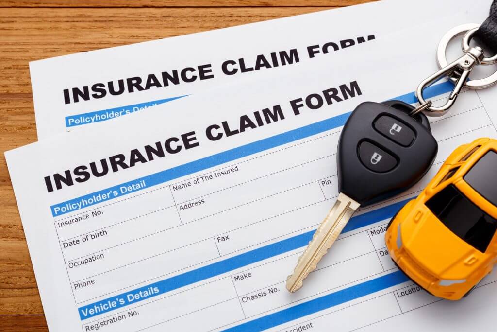 Car insurance claim concept with car key on wood desk