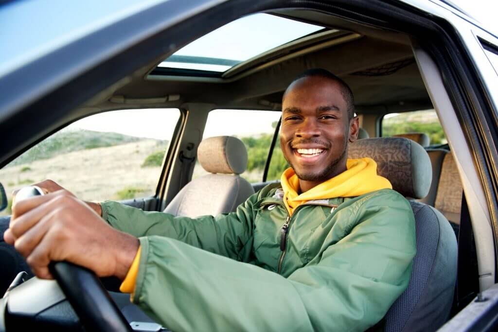 Portrait of smiling young african american man driving car