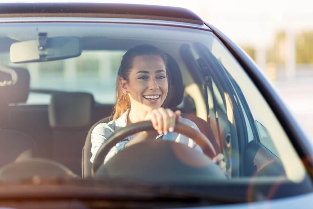 Happy woman driving a car and smiling