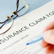 photo of insurance claim form and person holding a pen