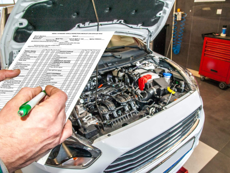 man holding a checklist for a car maintenance