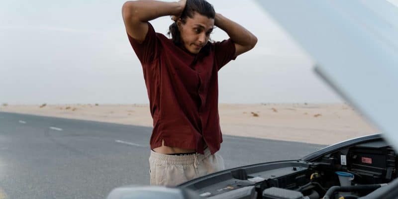 Man standing in front of car with hands on his head out of frustration