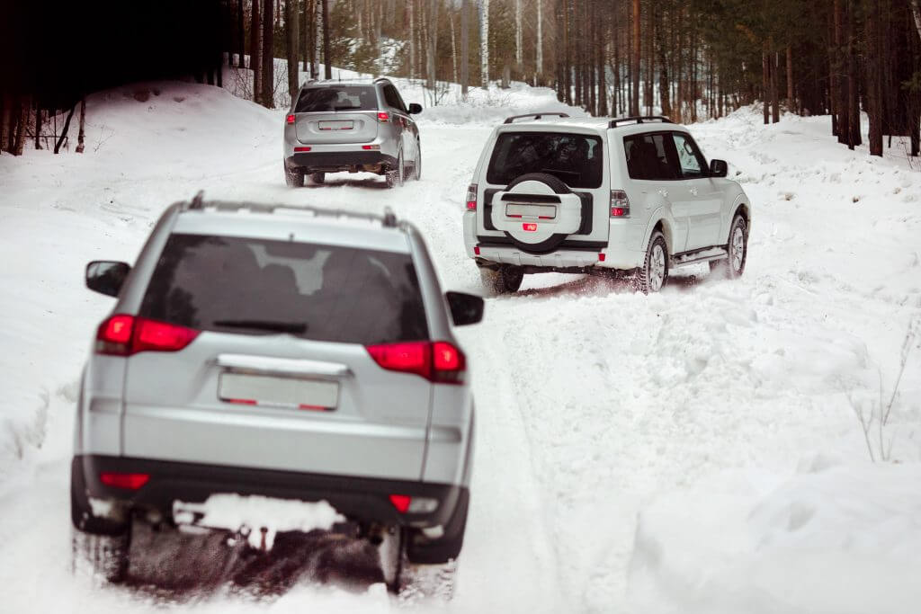 Three SUVs in the woods in winter in the rally. Driving SUV car in winter on forest road with much snow