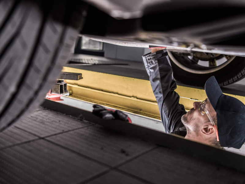 Mechanic Servicing Car. Checking Undercarriage Elements. Vehicle Maintenance.