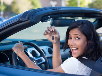 Closeup portrait, young cheerful, joyful, smiling, gorgeous woman holding up keys to her first new sports car. Customer satisfaction