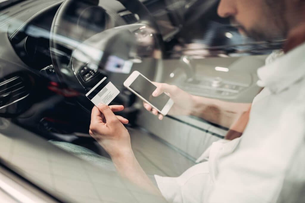 businessman with smartphone and credit card shopping online in the car