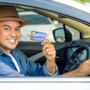 An Asian man is holding a credit card in his hand. While he was driving This picture is about shopping. Spending money Expenses related to car bills by credit card
