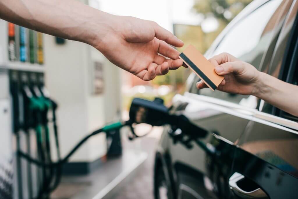 Cropped view of woman giving credit card to worker of gas station while fueling auto