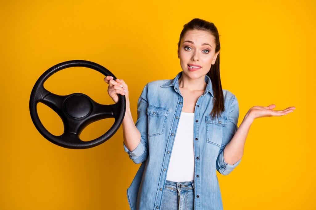 Photo of frustrated girl drive car hold steering wheel shrug shoulders bite, lips teeth have no license wear denim jeans shirt isolated over bright shine color background