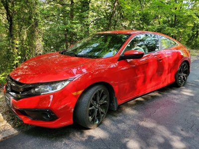 A bright red 2021 Honda Civic parked by the woods