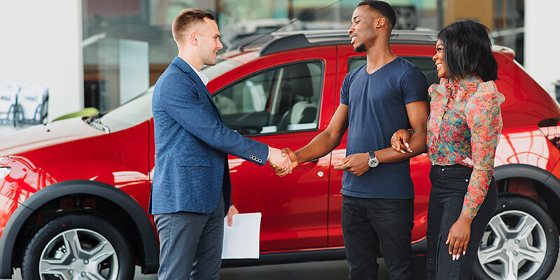 man shaking the hand of a car salesman