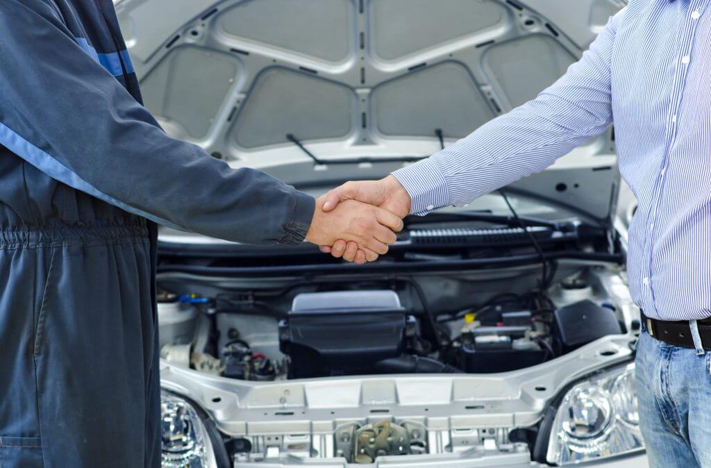 Car service. Mechanic and customer shaking hands. Excellent coop