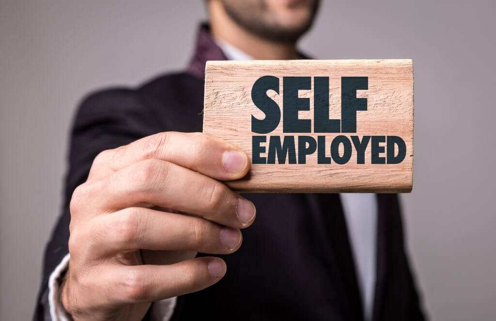 man holding a sign saying self employed