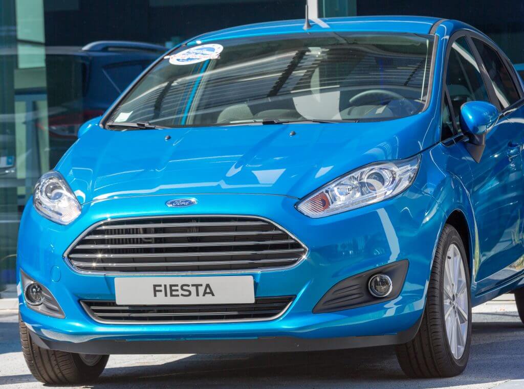 Puilboreau, France - August 7, 2016 : Closeup of blue Ford Fiesta name plate and car outsode showroom for display at Puilboreau, France. The Ford Fiesta is a supermini marketed by Ford since 1976 over seven generations and manufactured globally.