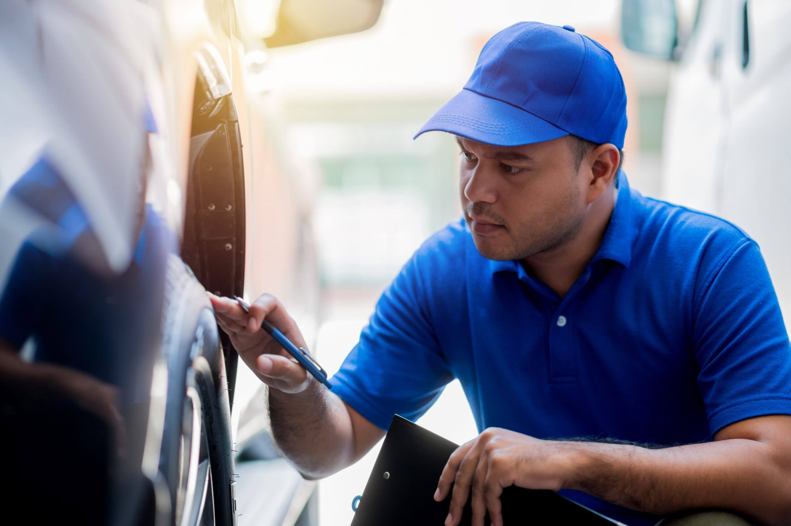 A car maintenance worker is checking the quality of the tires that are worn out, should they be replaced or not He takes care of the car for the customer.