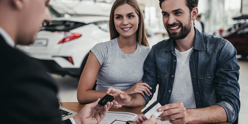 man and woman talking to a car salesman