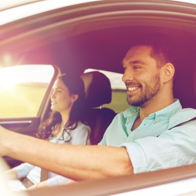 leisure, road trip, travel, family and people concept - happy man and woman driving in car