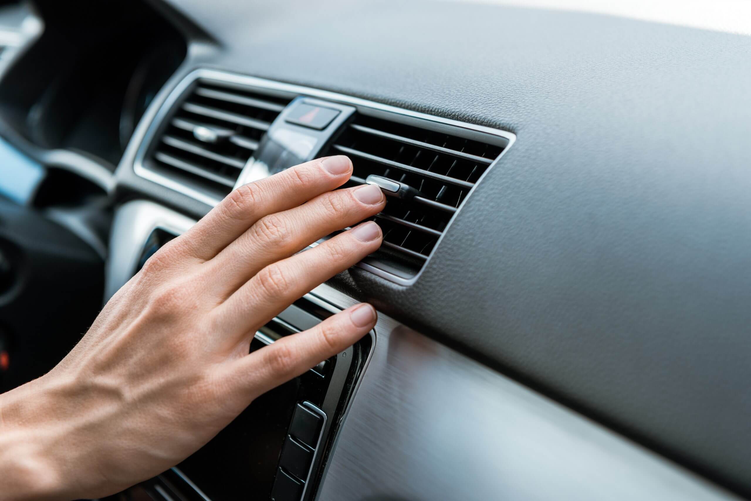 cropped view of man touching air conditioner switch in car