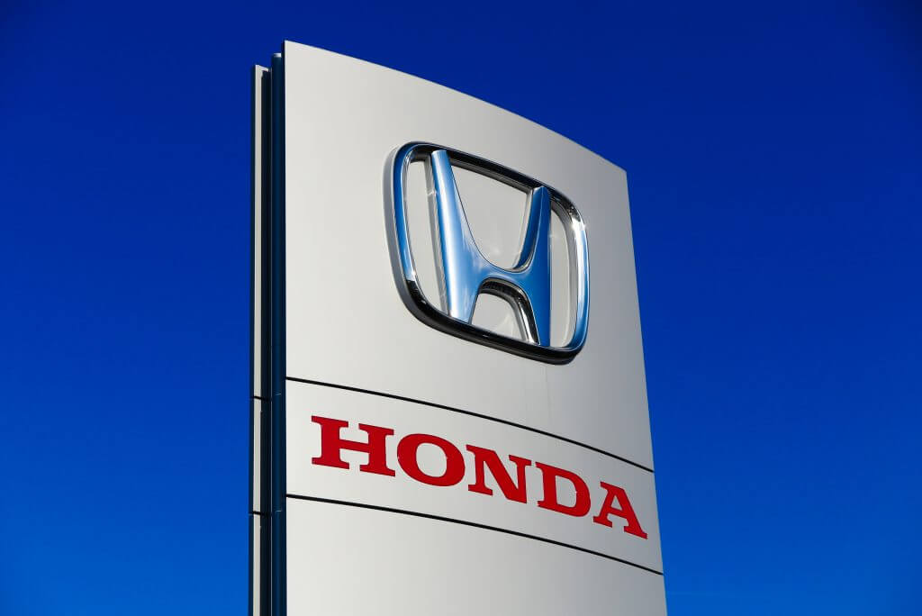Dinslaken, Germany - December 18. 2019: Isolated red silver logo lettering of japanese automobile manufacturer Honda against cloudless blue sky