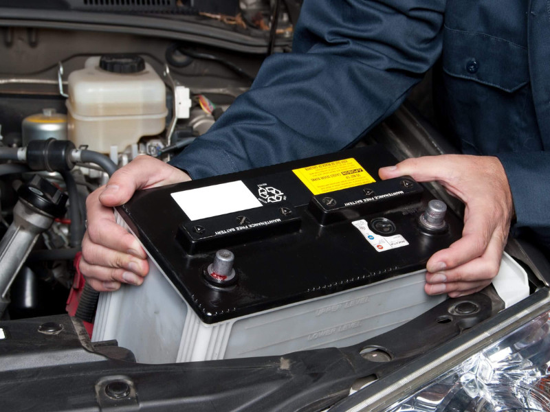A car mechanic replaces a battery.