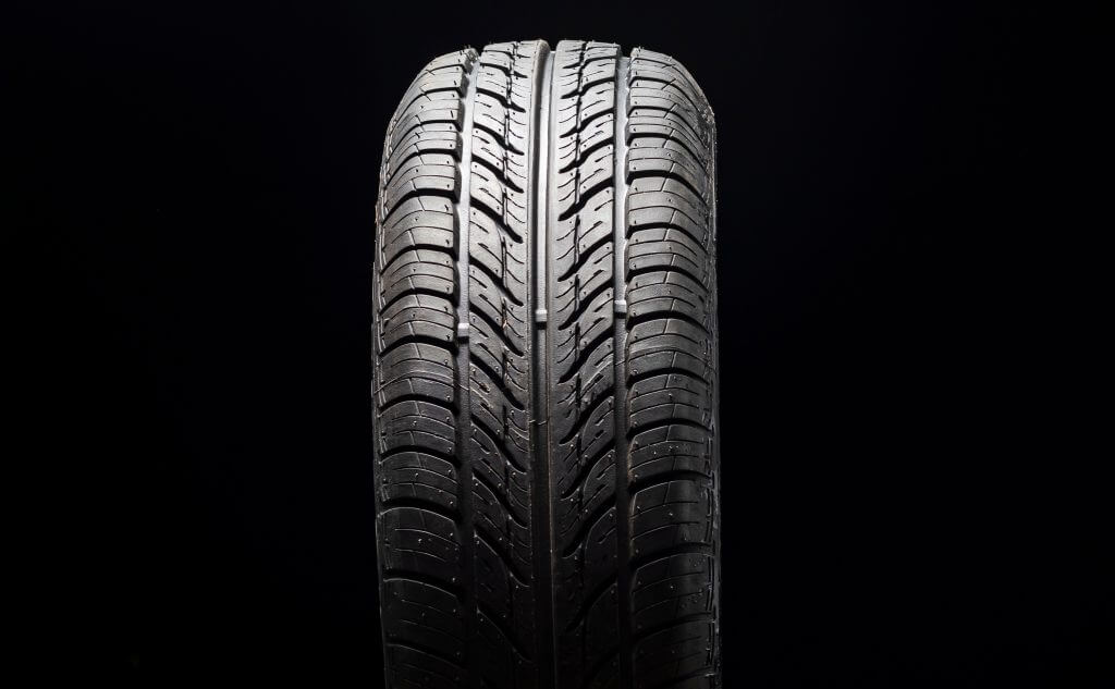 Car tire in dark color. Night shooting. The tread is summer. Light falls from above