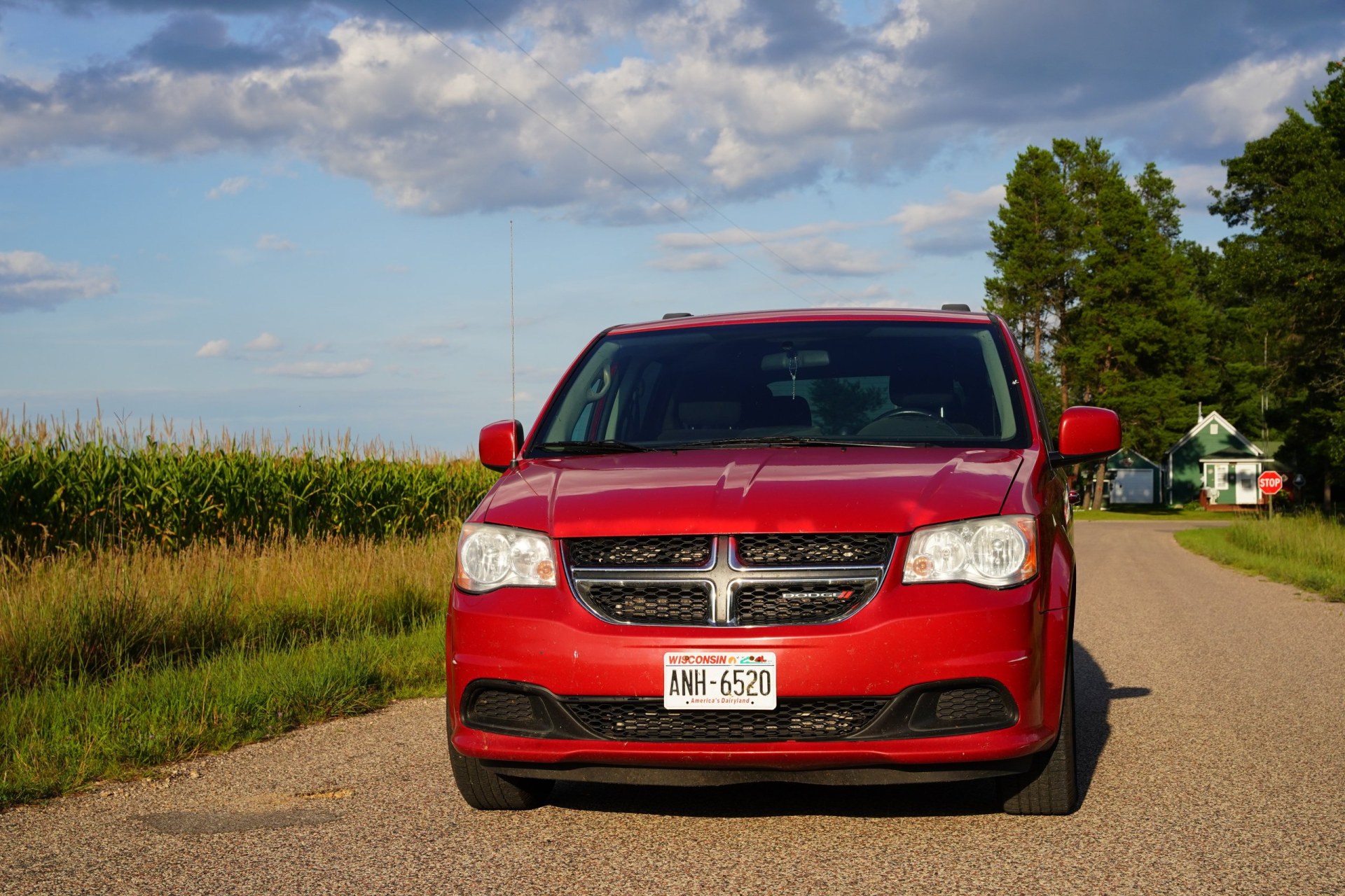 2013 family passenger Red Dodge Grand Caravan sits parked in the countryside