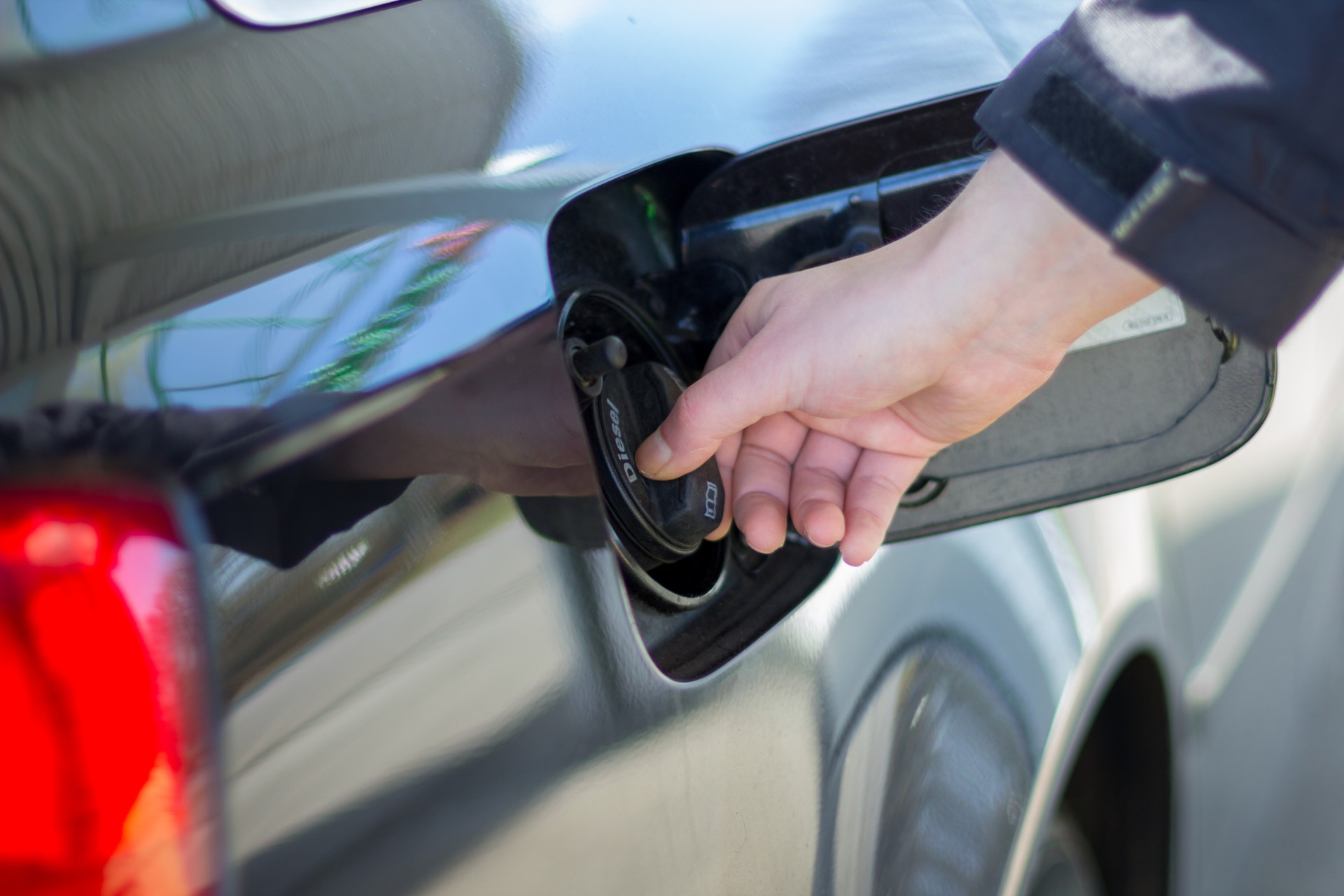 A hand tightening the gas cap on a car.