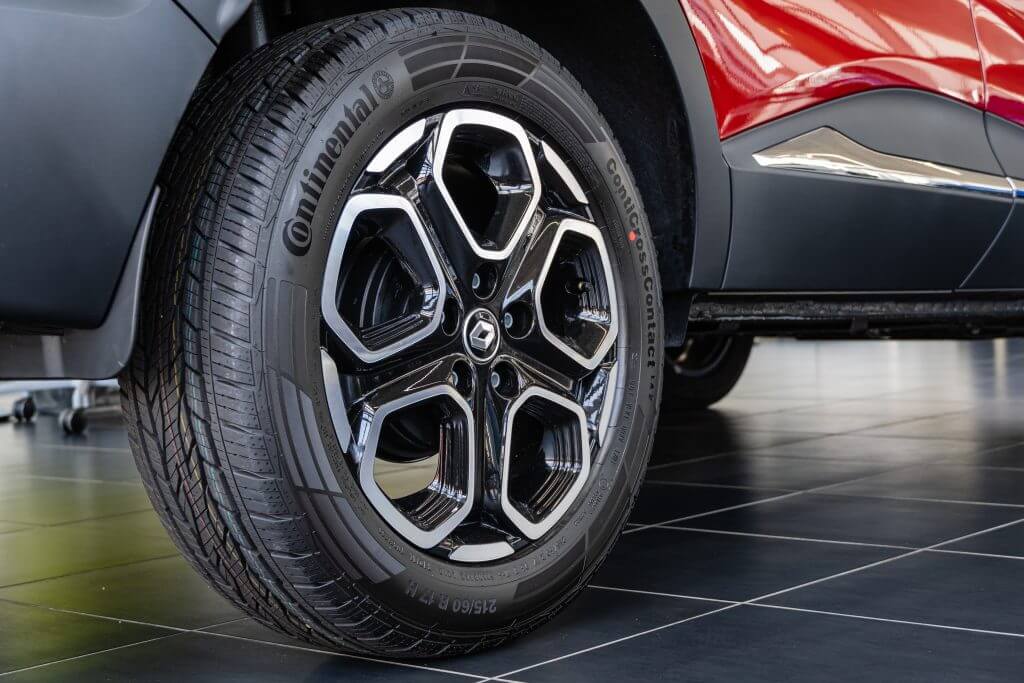 Red SUV Renault Captur at showroom. Continental tire is mounted on cast aluminum rim. Close-up of rear right wheel. Renault car dealership in Mega Adygea. Krasnodar, Russia - August 26, 2021