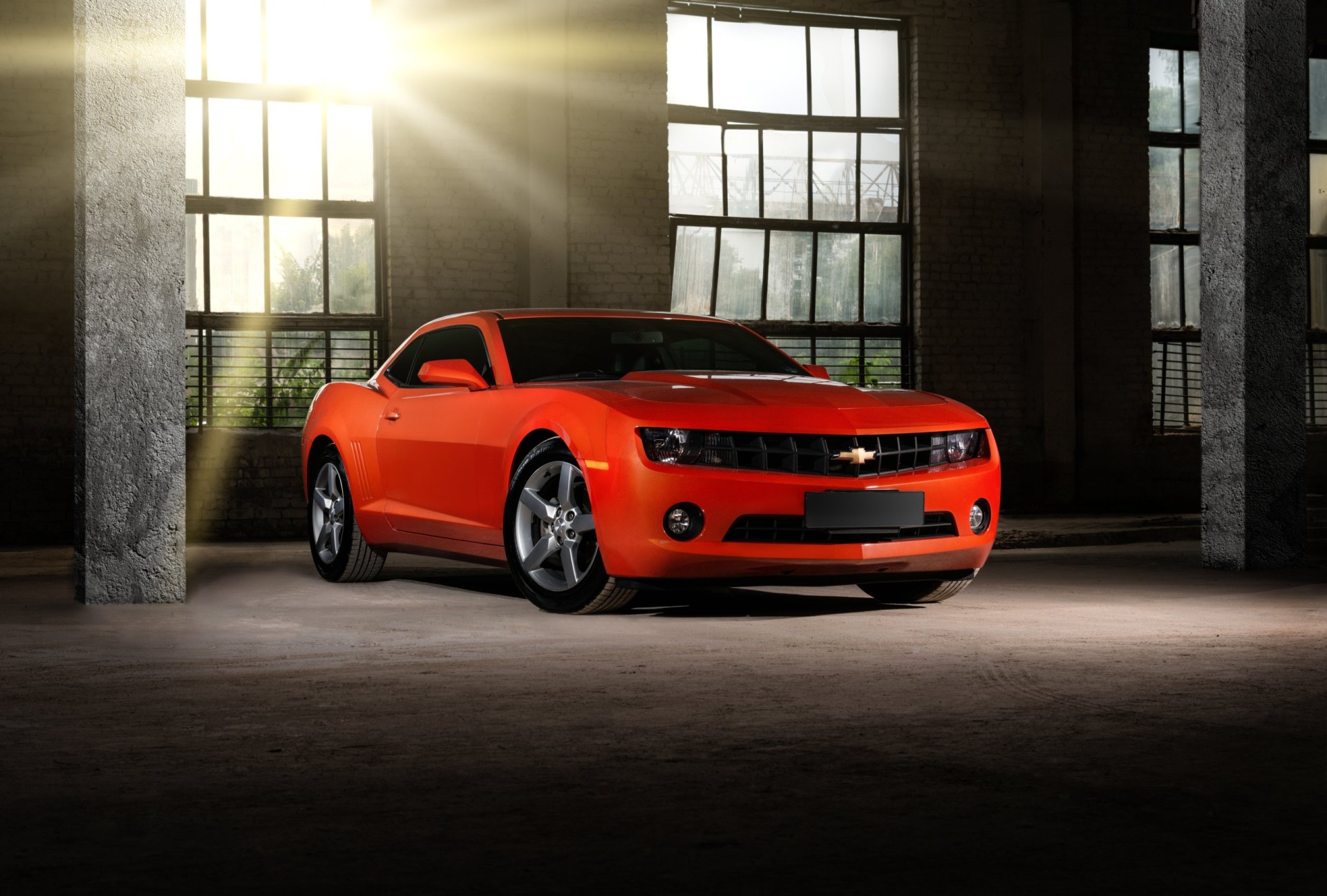 2010 Orange Chevrolet Camaro in dark industrial building