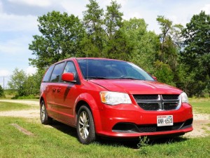 2013 family passenger Red Dodge Grand Caravan sits parked in the countryside