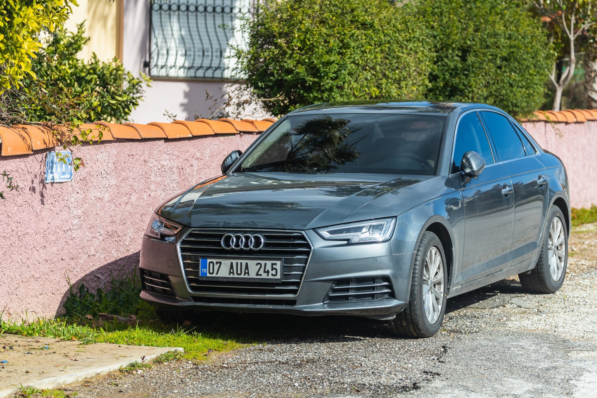 Silver 2018 Audi A4 is parked on the street on a warm day against the backdrop of a park
