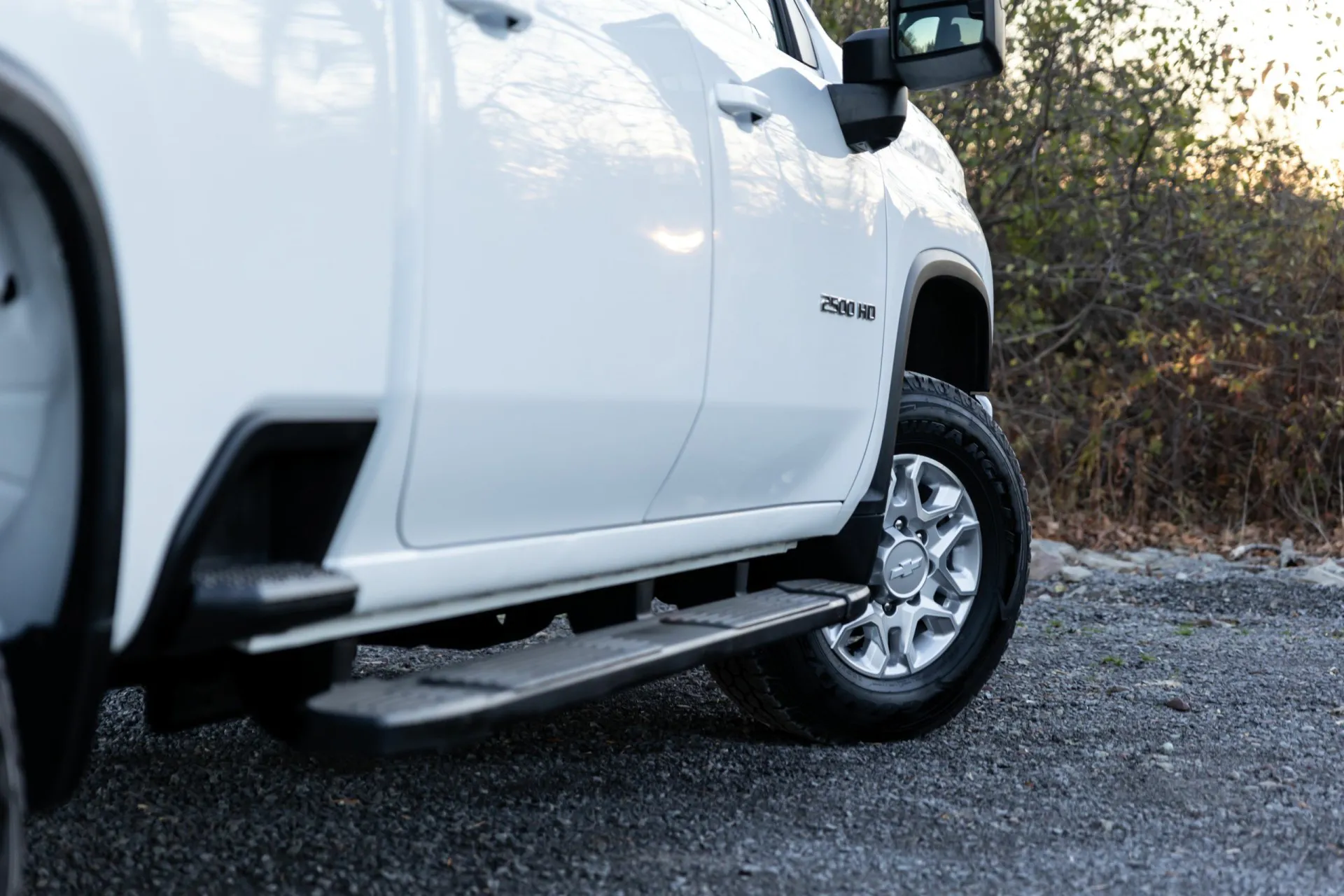 White Chevy Silverado 2500 surrounded by woods outdoors