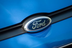 Closeup of Ford logo on blue car front parked in the street