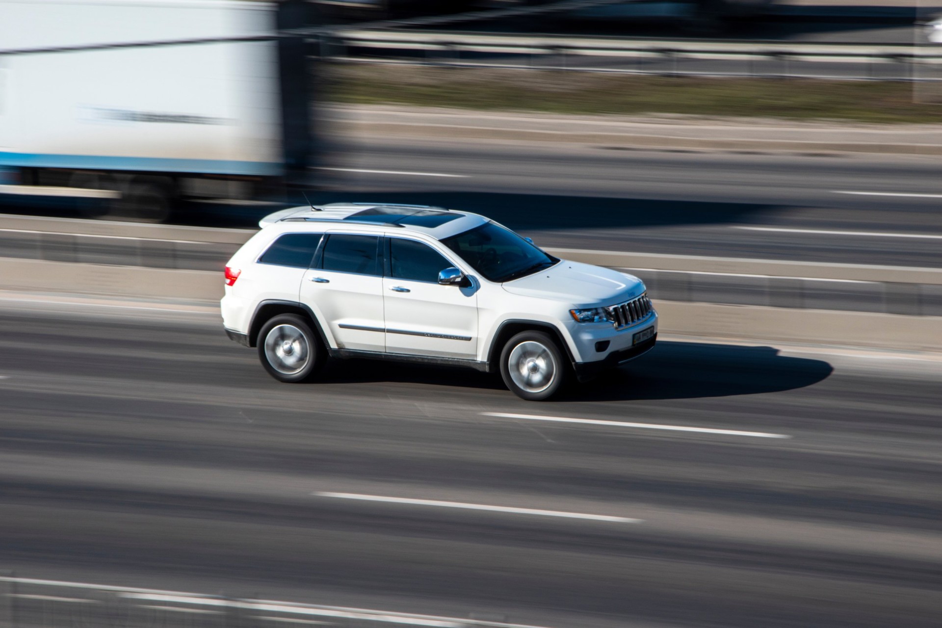 White 2012 Jeep Grand Cherokee car moving on the street