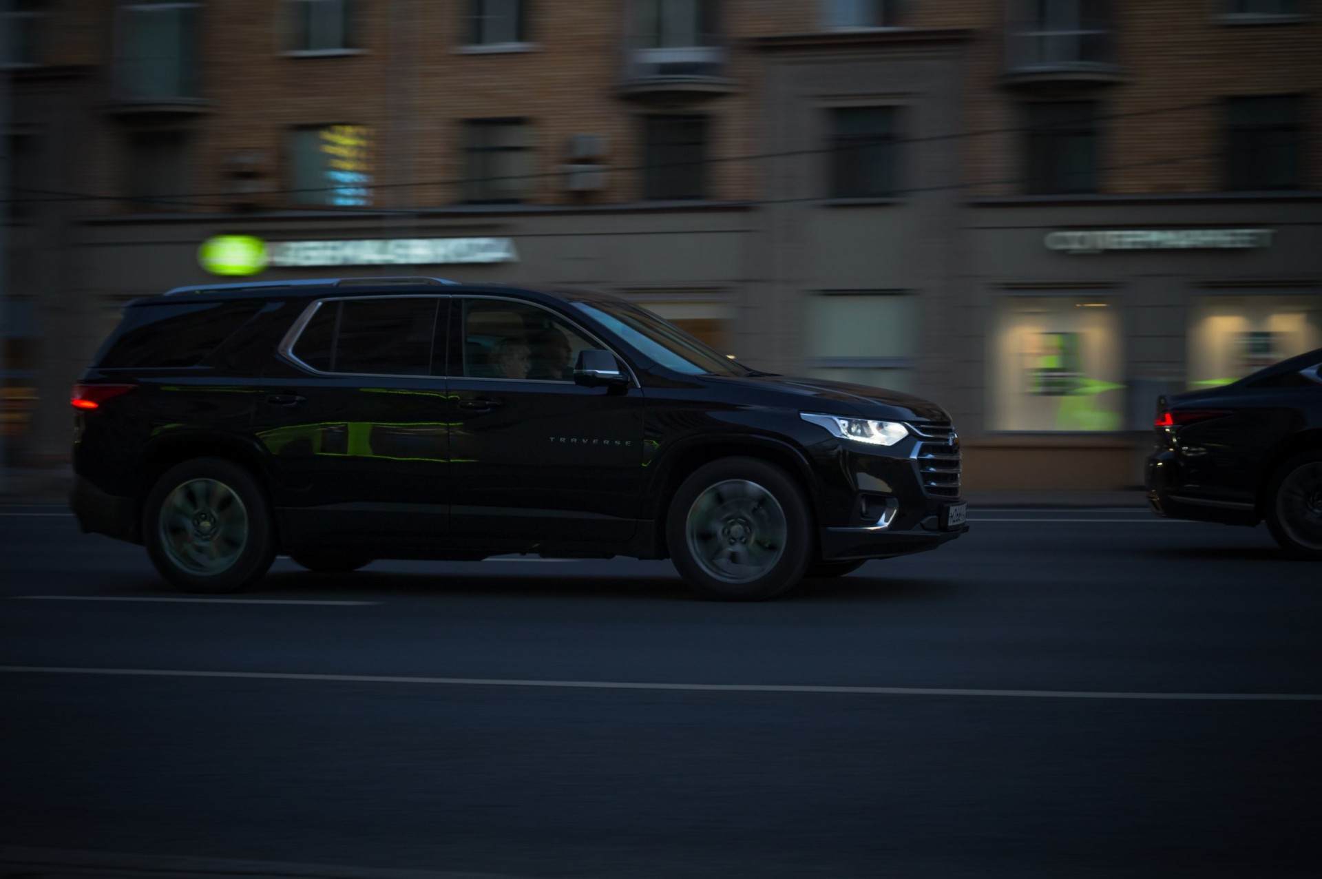 Side view of Chevrolet Traverse drive on high speed. Driving auto at night on city road.