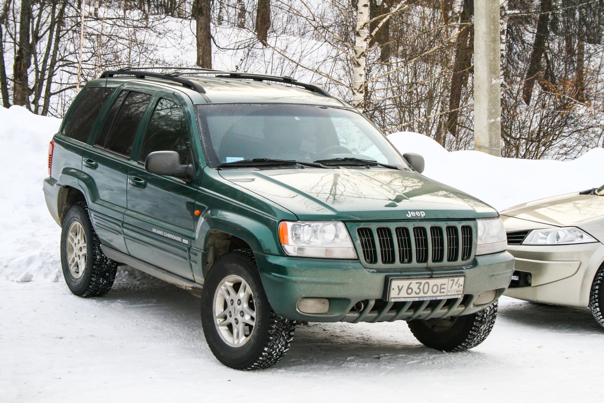 Green offroad Jeep Grand Cherokee at the snow covered countryside.