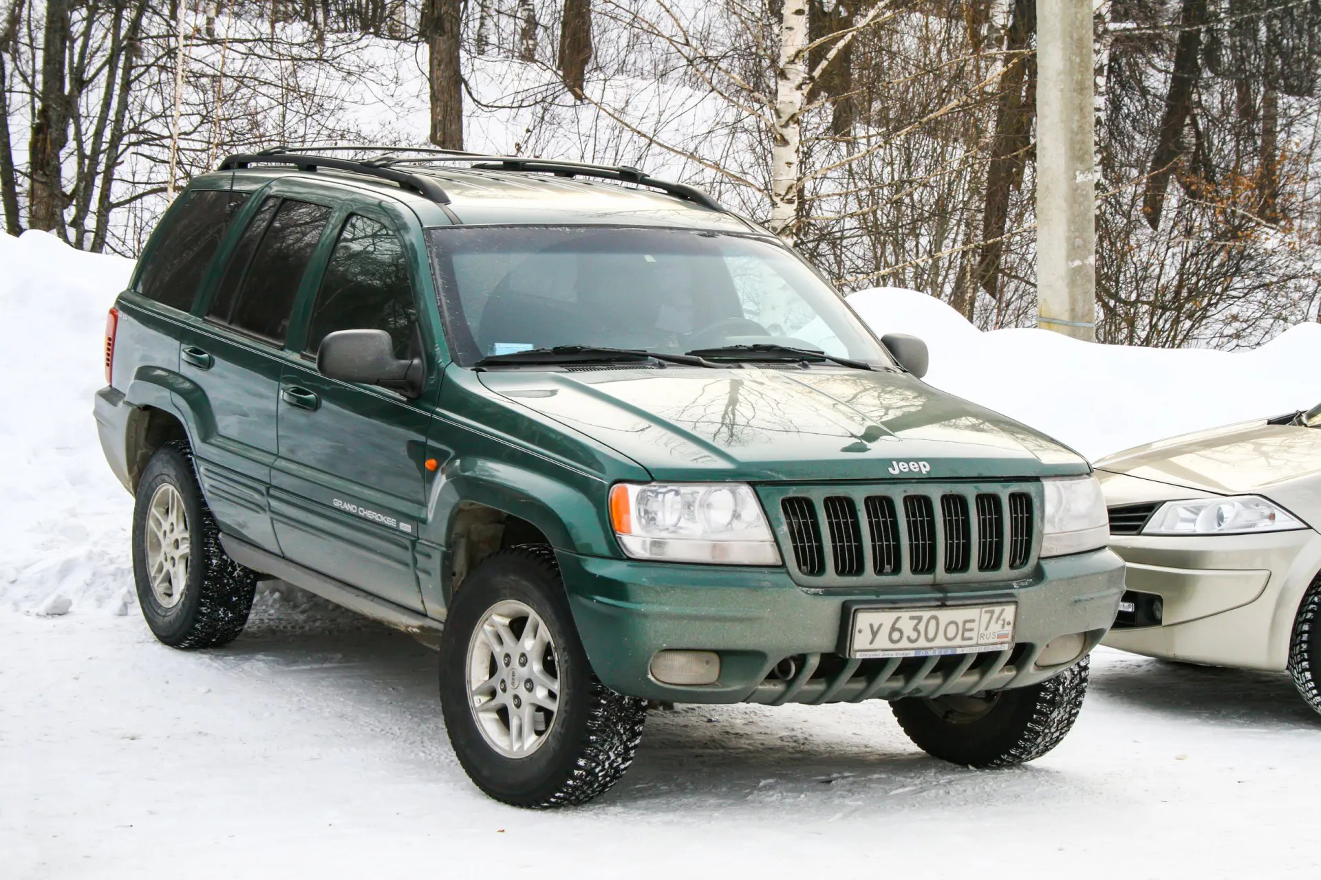 Green offroad Jeep Grand Cherokee at the snow covered countryside.