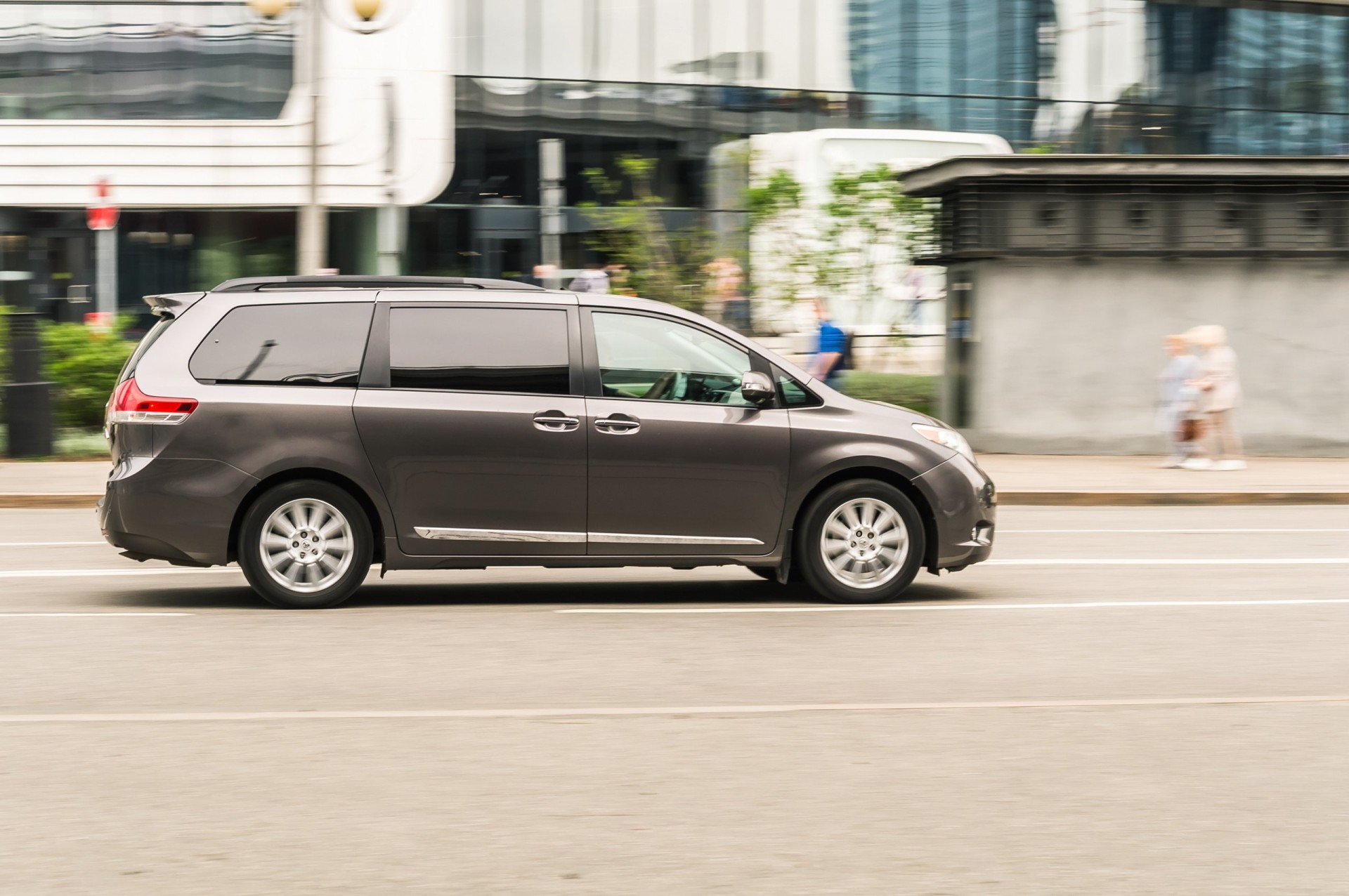 Toyota Sienna in motion on the city street driving on the road, side view.