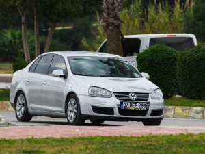White Volkswagen Jetta driving on the street on a warm summer day