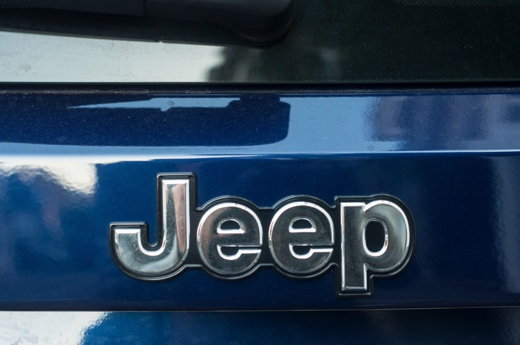 Closeup of Jeep logo on blue car rear parked in the street