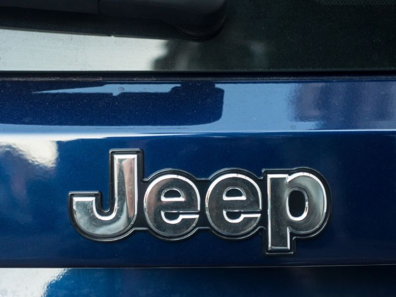 Closeup of Jeep logo on blue car rear parked in the street